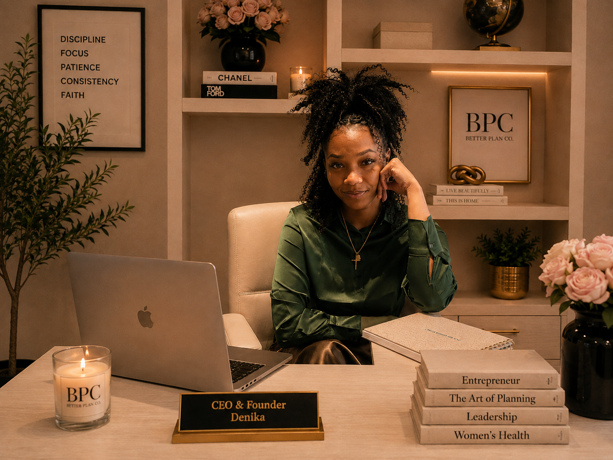 A woman sits at a desk in a warm, styled office or home office setting, wearing a green hoodie. In front of her is an open laptop, a candle, and a nameplate that reads 'CEO & Founder Denika'.